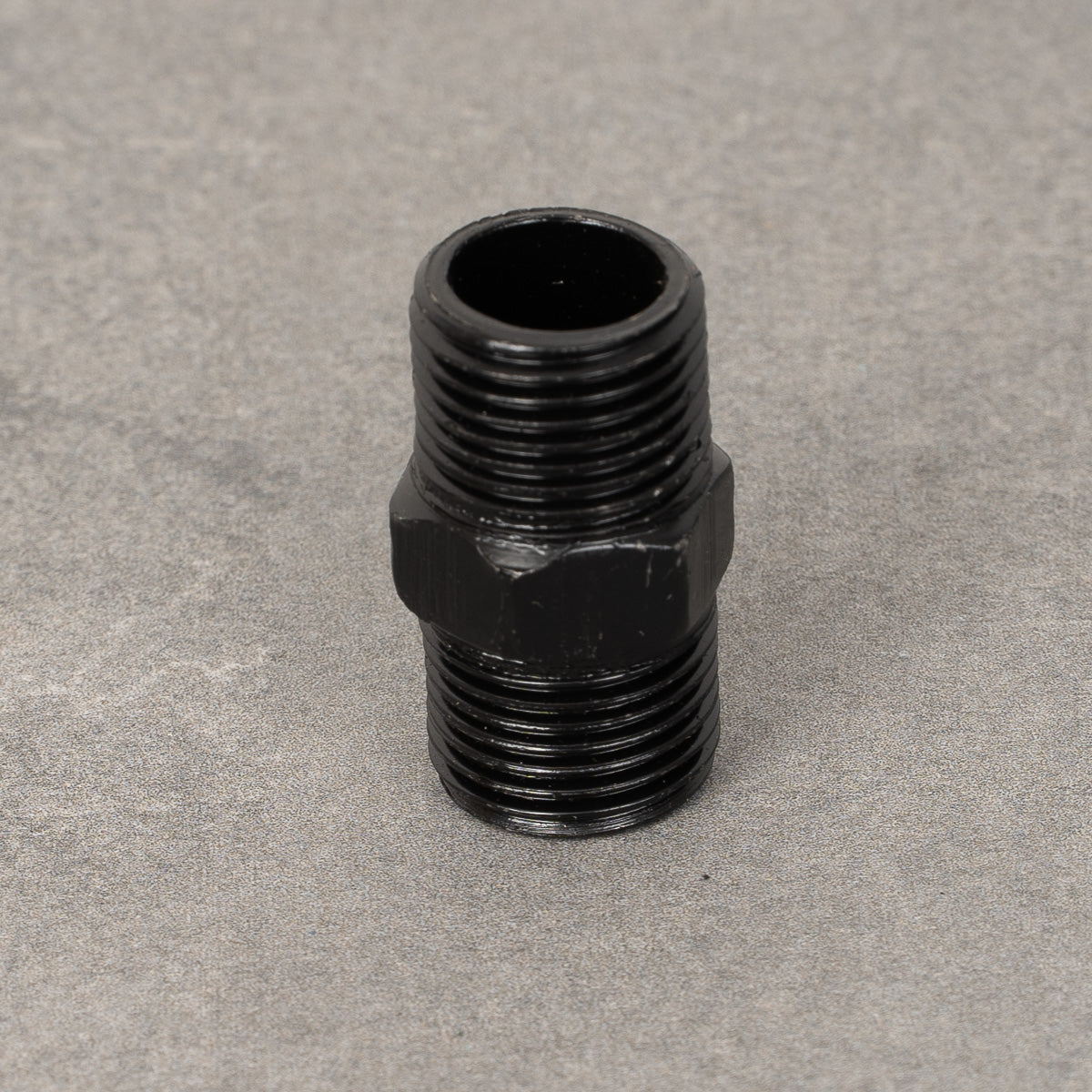 Dubbelnippel i svartlackerad metall, 20 mm i diameter, med gängade ändar för anslutning av rör.