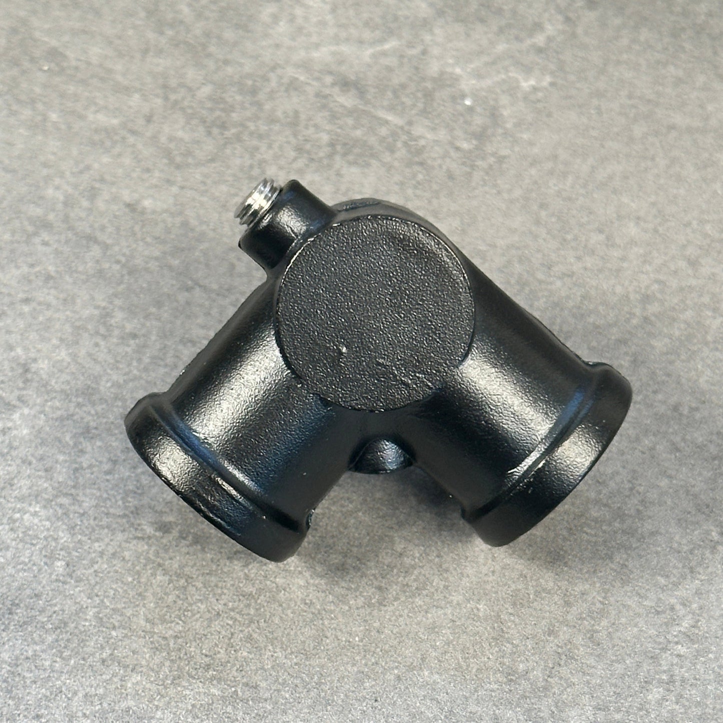 En svartlackerad tre-koppling i rostfritt stål med en diameter på 20 mm, avsedd för rörkopplingar.