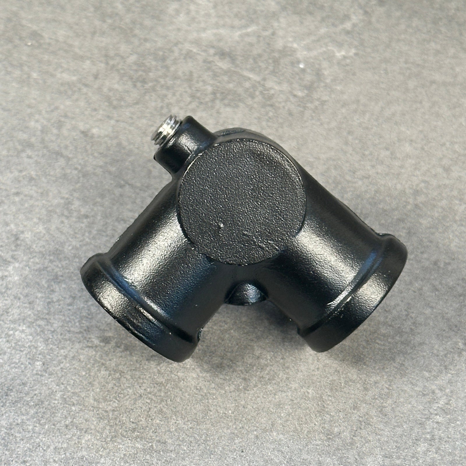 En svartlackerad tre-koppling i rostfritt stål med en diameter på 20 mm, avsedd för rörkopplingar.